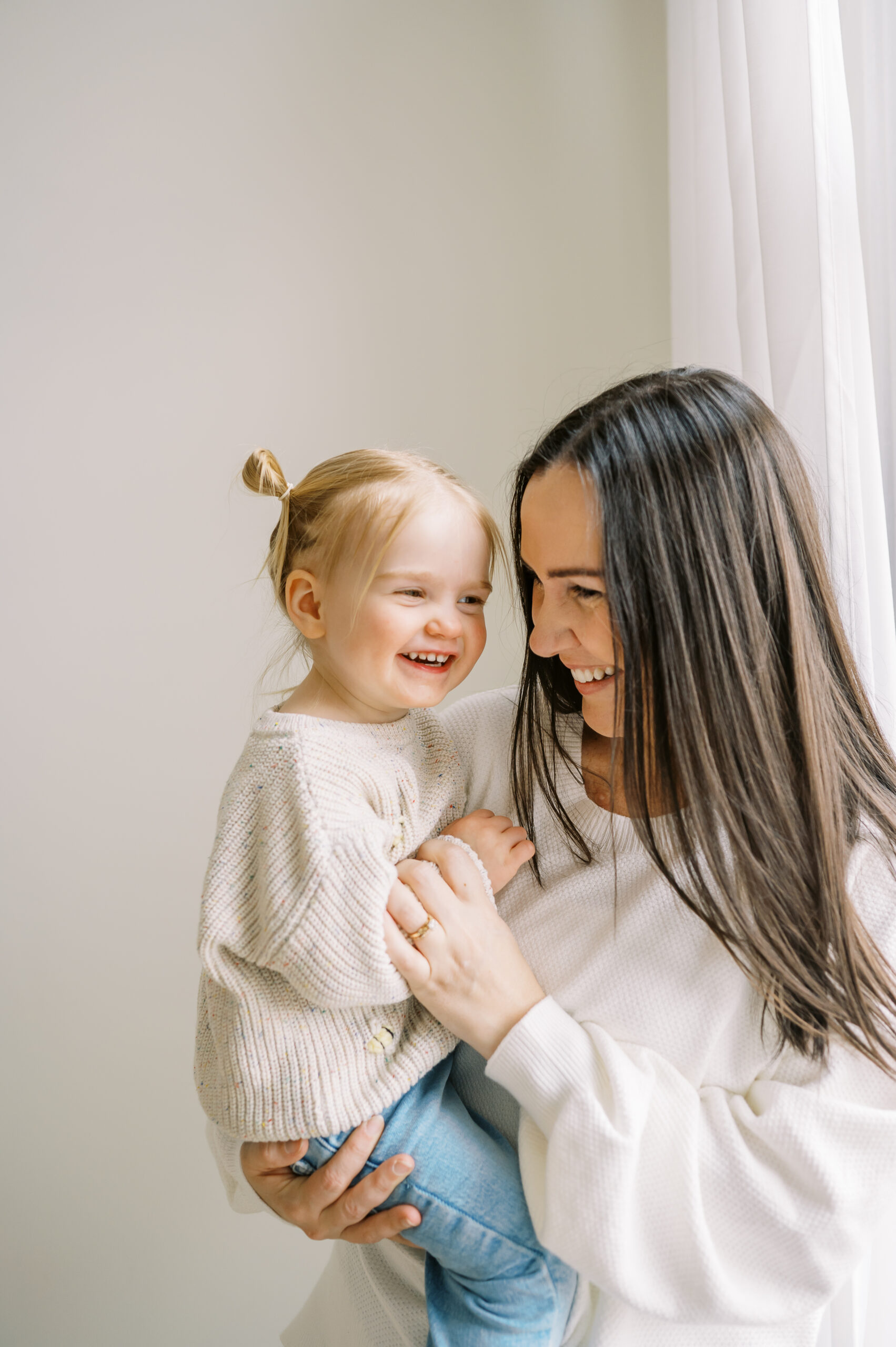 Mom holding toddler near window during family photo shoot