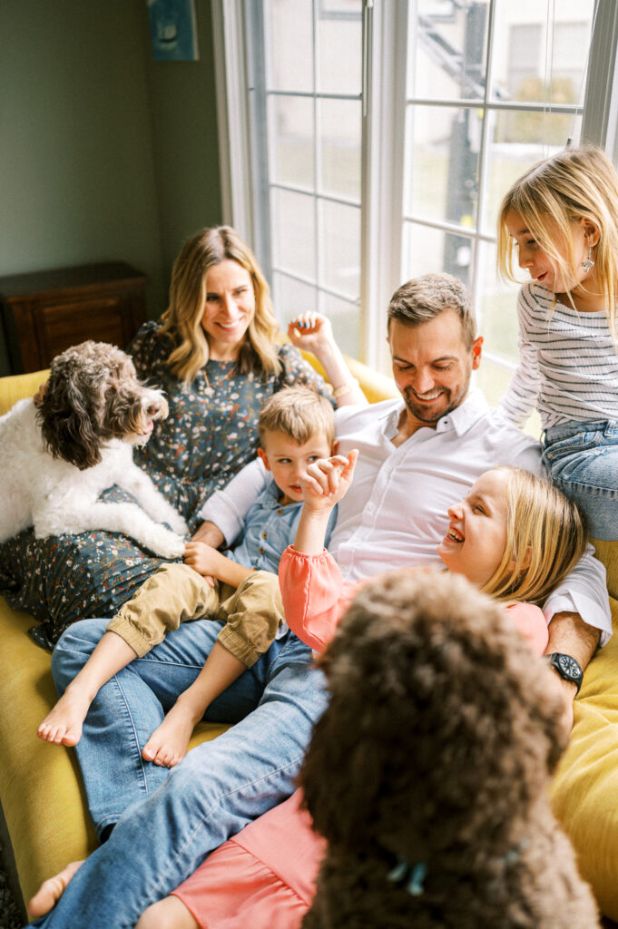 Family snuggled up together on yellow sofa near bright window by Powell, Ohio Photographer