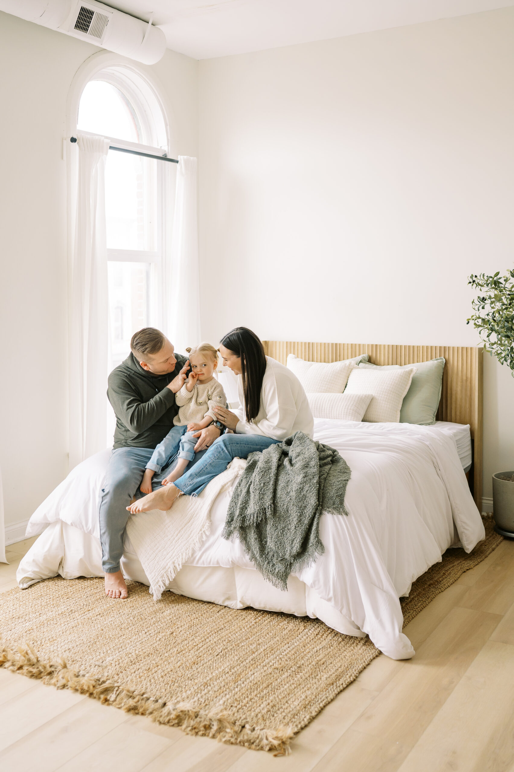 Family sitting on foot of bed snuggled up together